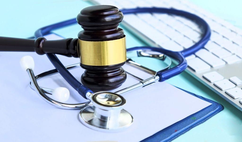 Gavel and stethoscope on keyboard, legal healthcare concept.