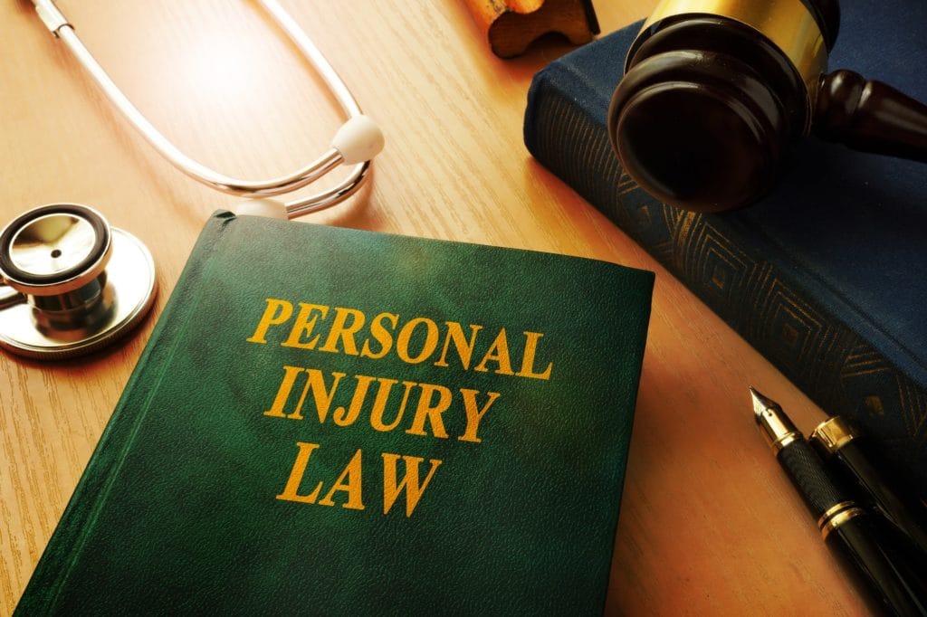 Personal injury law book, gavel, stethoscope on table.