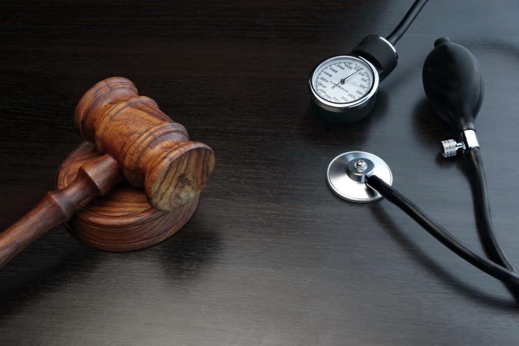 Gavel and sphygmomanometer on dark wooden table