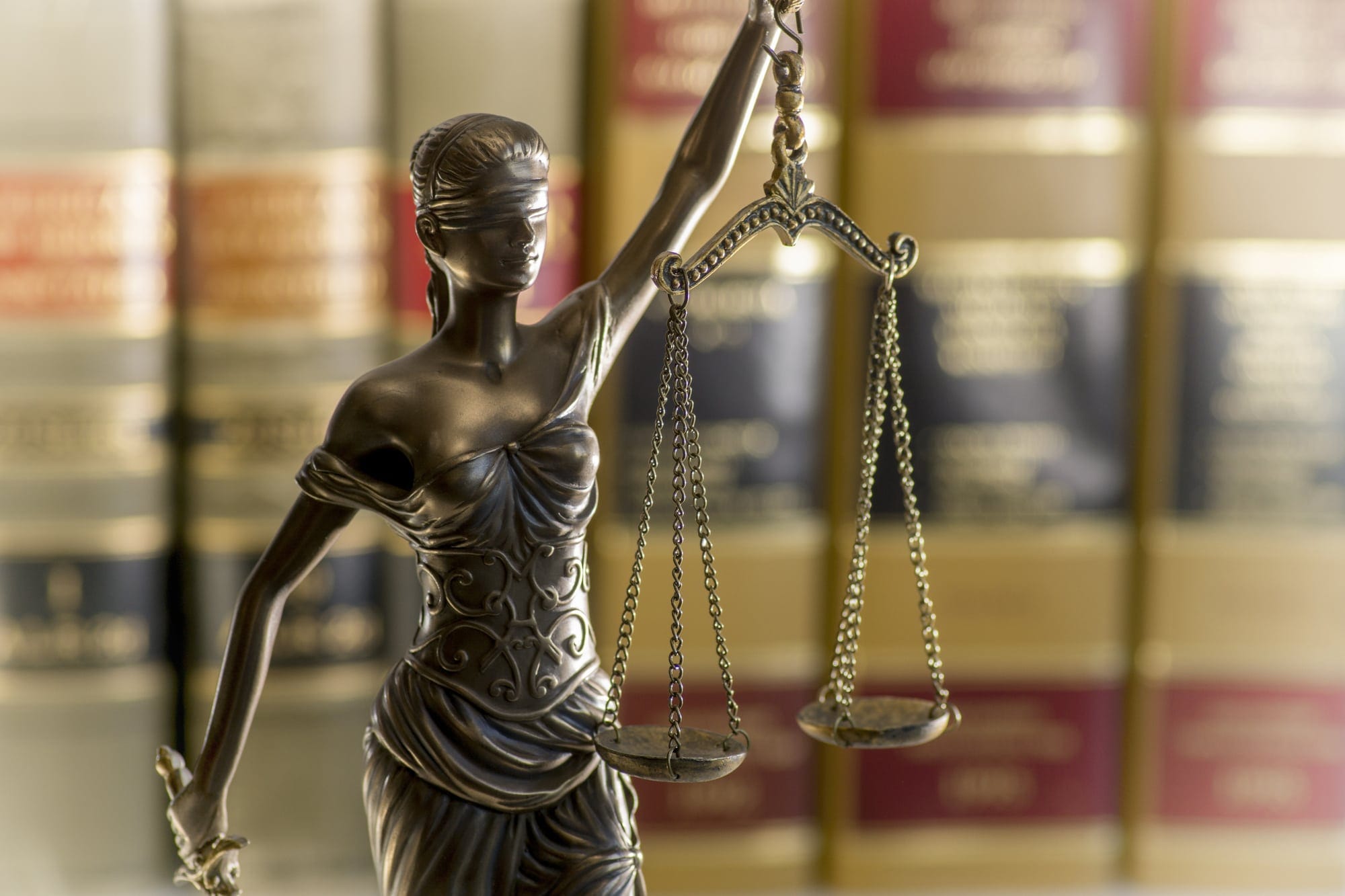 Lady Justice statue with law books background