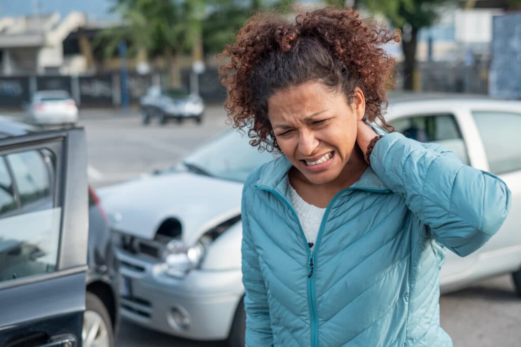 Woman in pain after car accident, holding neck.