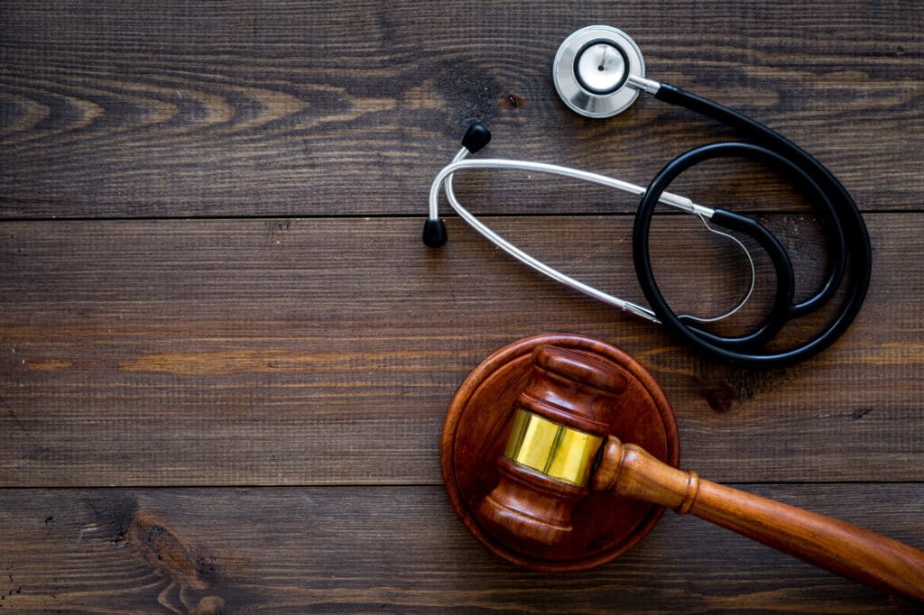 Gavel and stethoscope on wooden table.