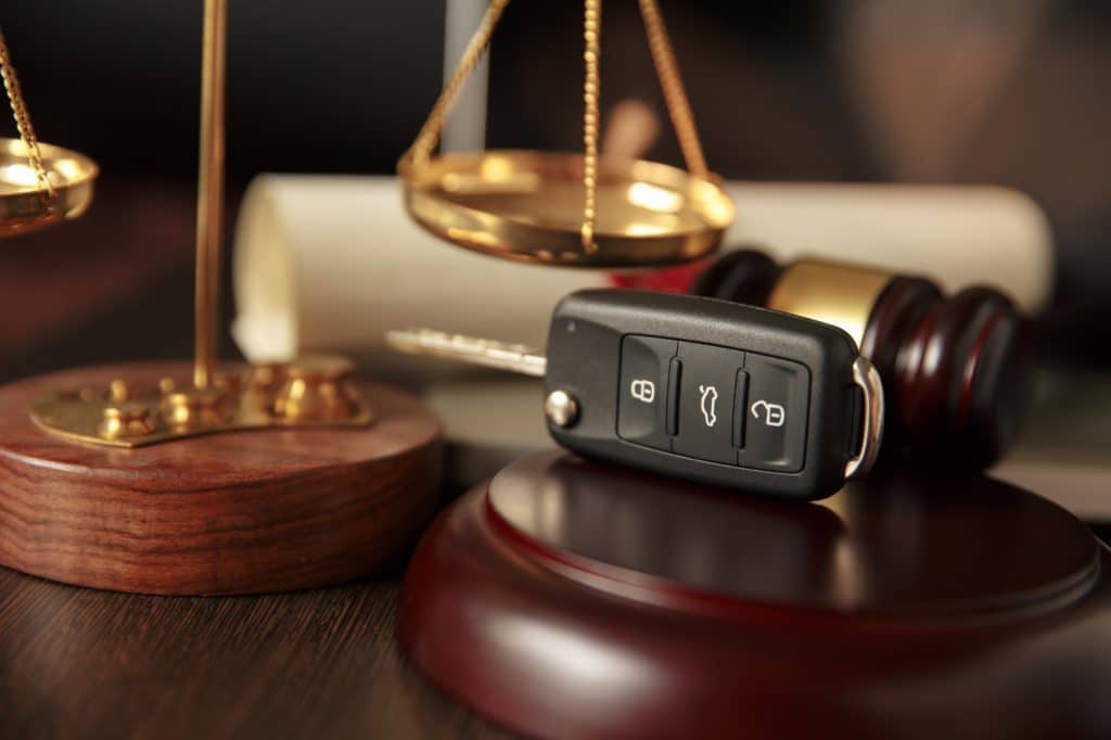 Car key, gavel, scales represent legal concept.