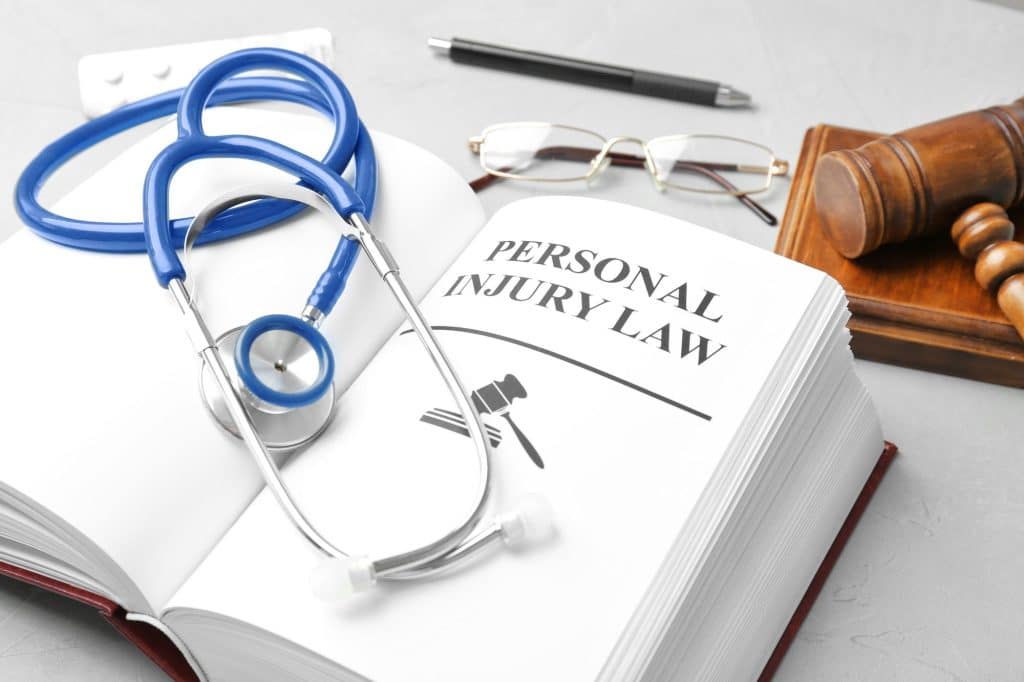 Personal injury law book, stethoscope, gavel, and glasses.