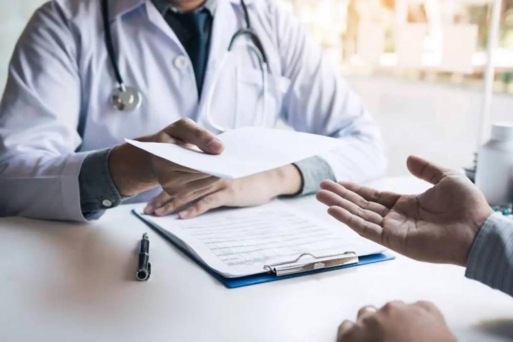 Doctor hands patient paperwork during medical consultation